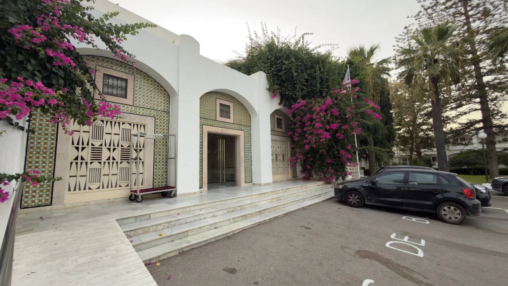 Eingang des Les Orangers Beach Resort in Hammamet mit weißen Bögen, bunten Fliesen und blühender Bougainvillea