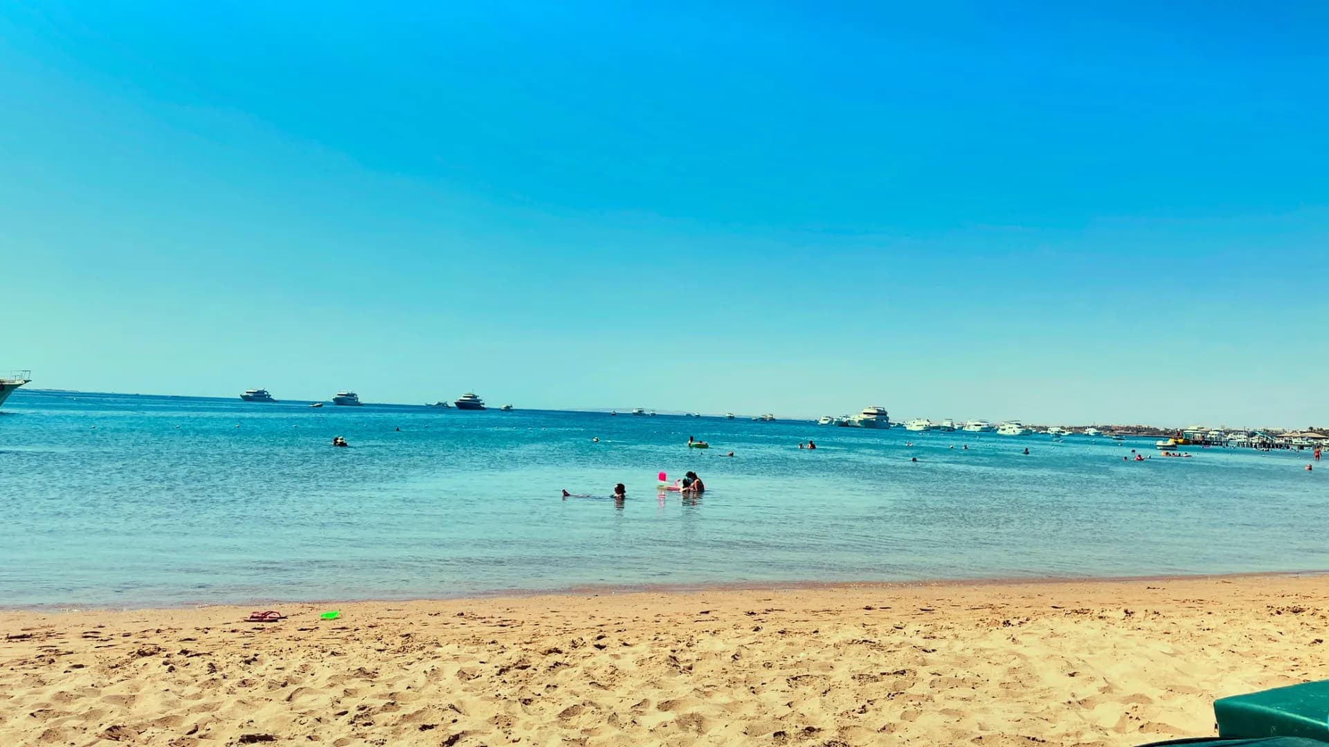Flach abfallender Sandstrand des Giftun Azur Resort in Hurghada mit türkisfarbenem Meer und Ausflugsbooten am Horizont